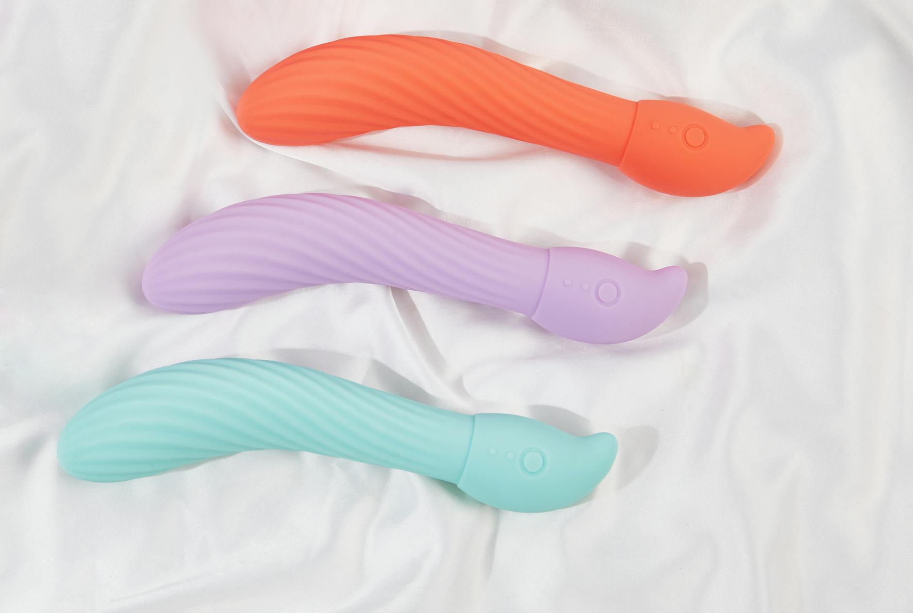 Mano che tiene un vibratore arancione su sfondo viola minimale, che mostra la sensualità moderna