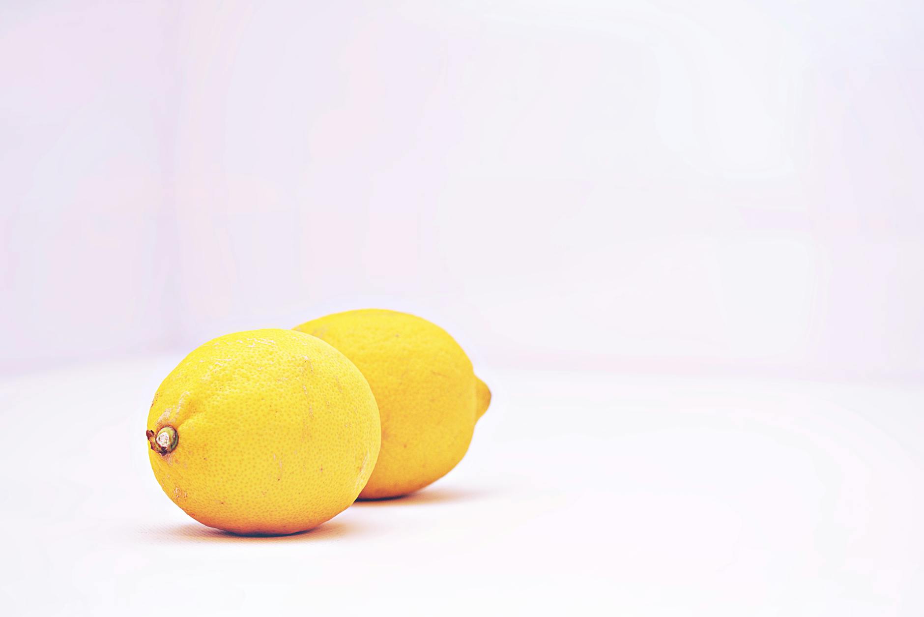 Due limoni vibrant su uno sfondo bianco minimalista, simboli di freschezza e sensibilità delicata.