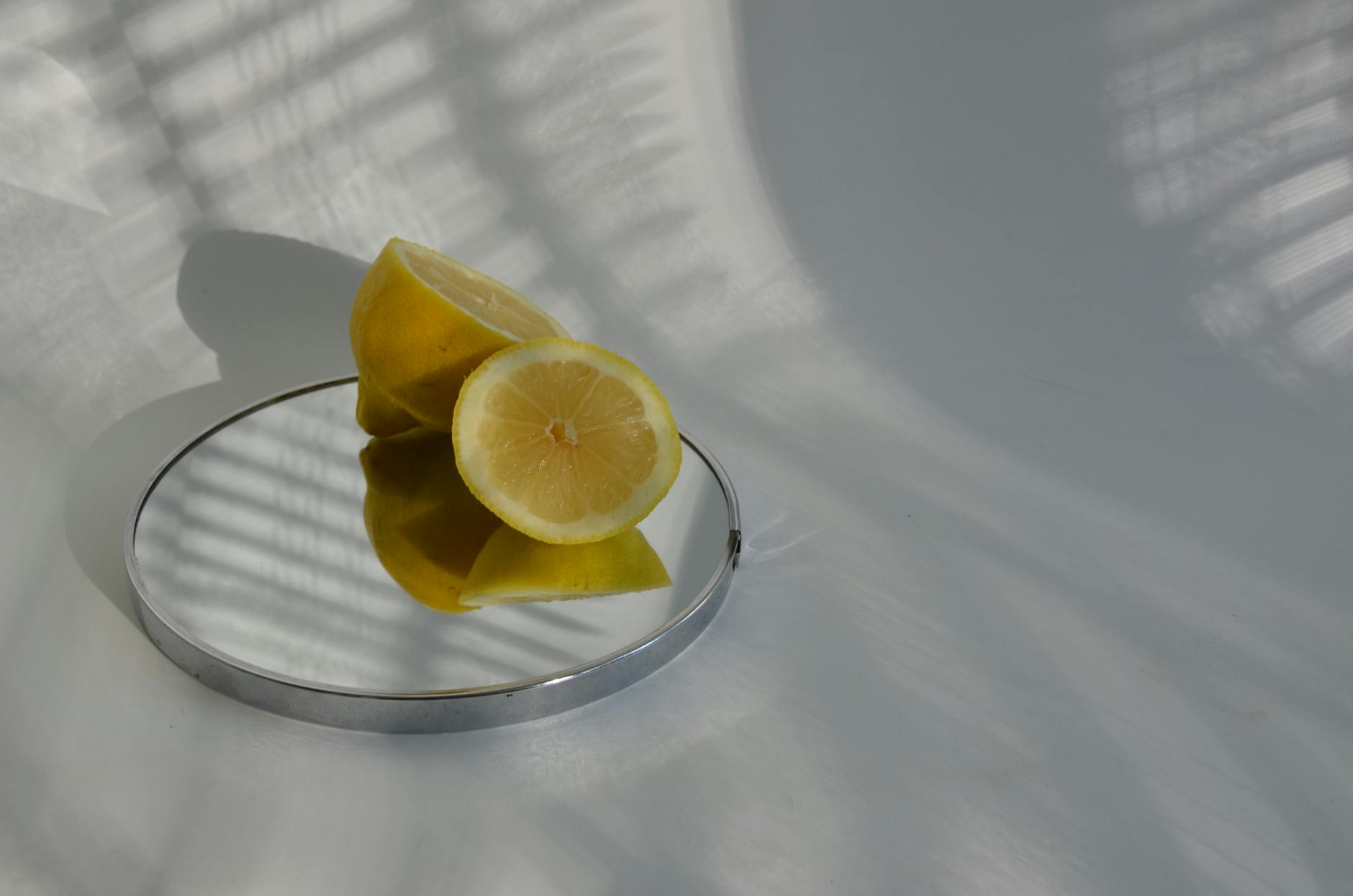 Limoni affettati su uno specchio che creano ombre, in uno stile minimalista di fotografia alimentare.