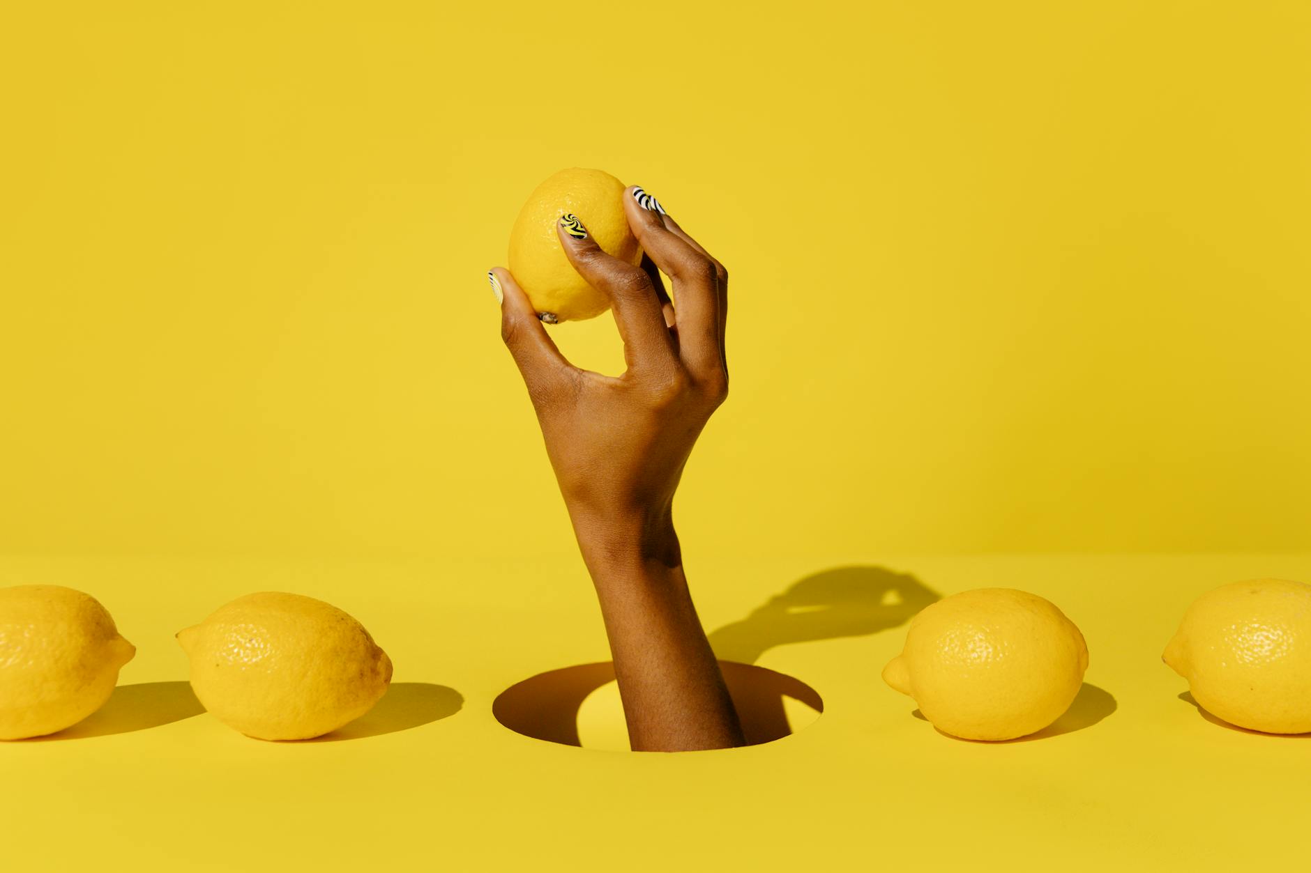 Una mano che tiene un limone fresco su sfondo giallo vivido, simboleggiando freschezza e desiderio consapevole
