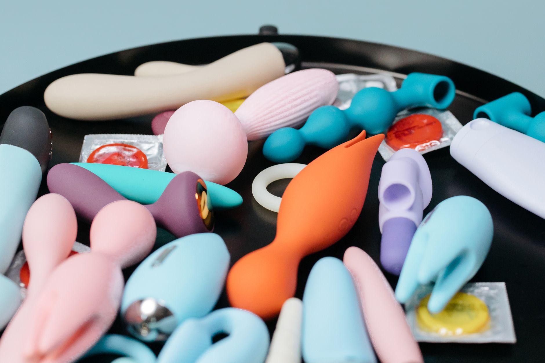 Mani che tengono giocattoli sessuali in silicone dai colori pastello