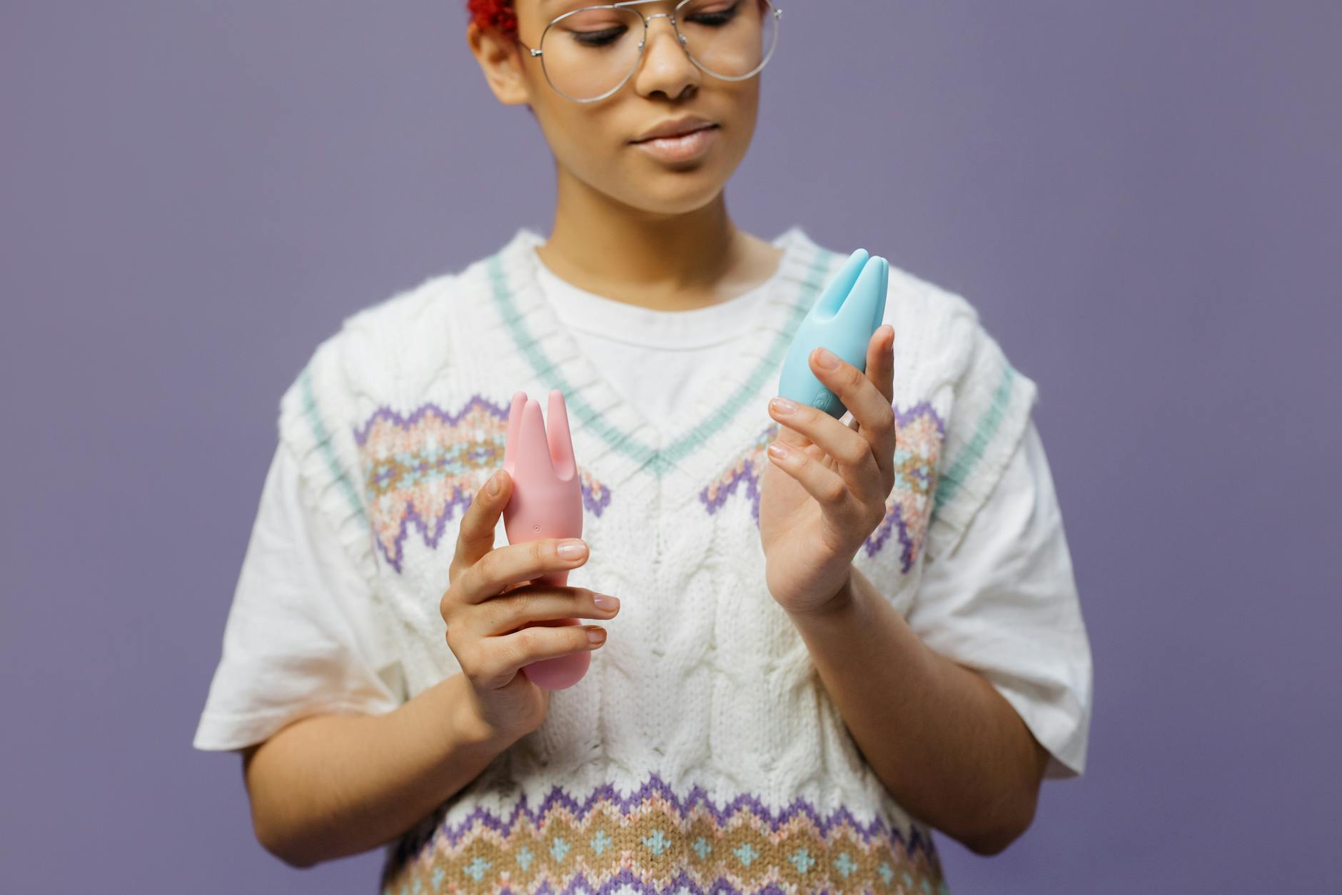 Donna che tiene in mano vibratori in silicone blu e rosa, con uno sguardo consapevole e consapevole.